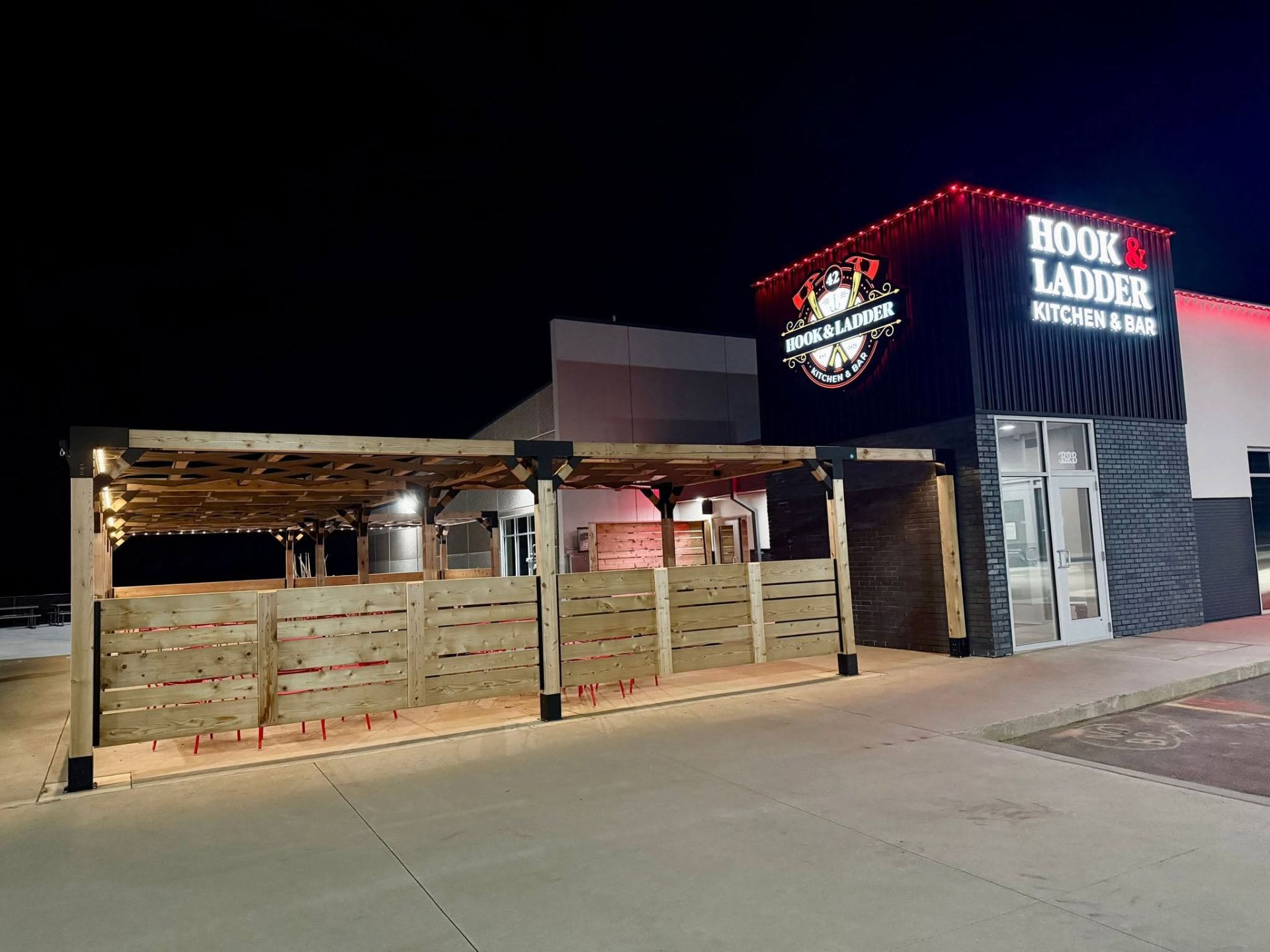 Custom pergola and outdoor wood structure at night by Qualified Carpentry at Hook and Ladder Kitchen and Bar Sioux Falls South Dakota